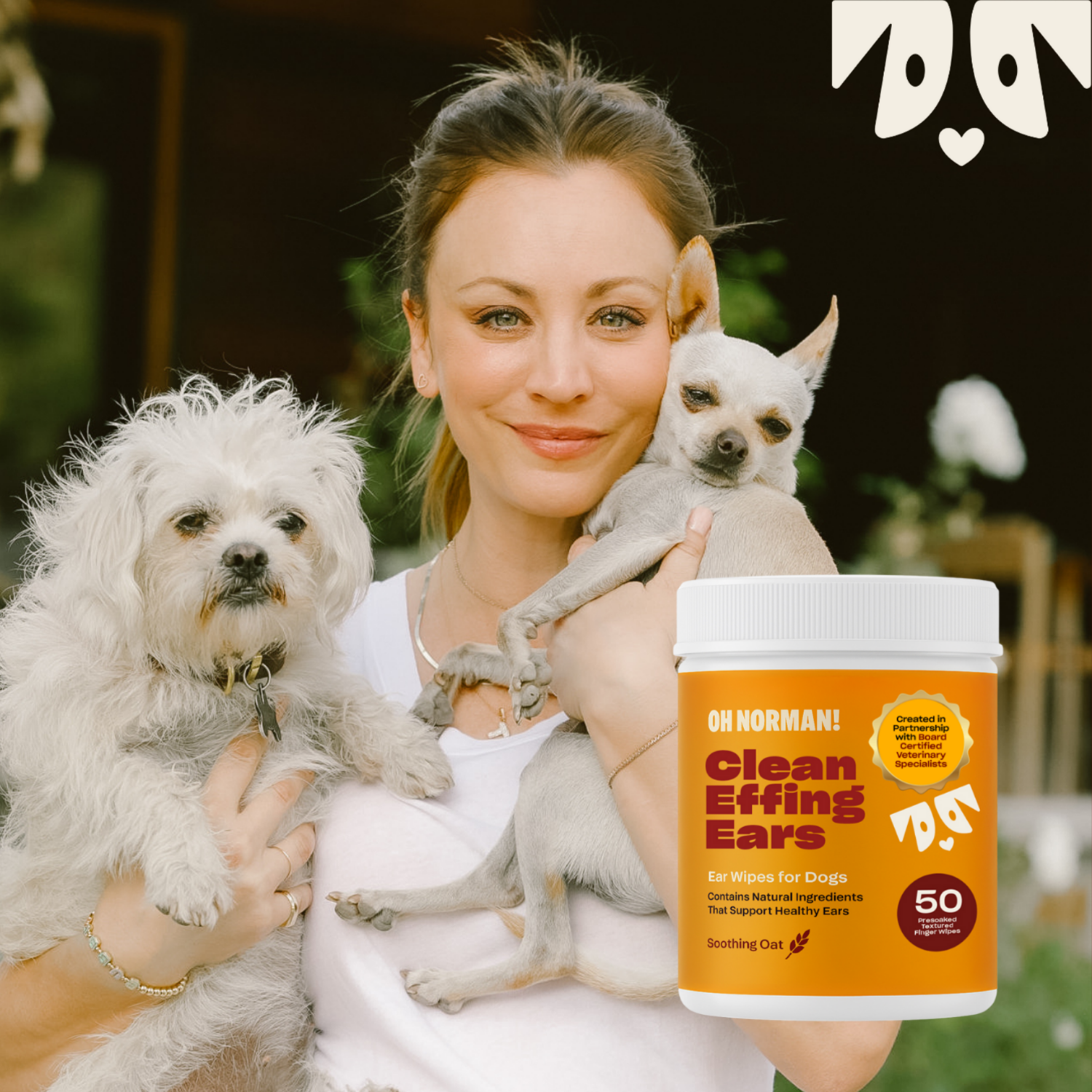 Kaley Cuoco holding two small dogs with 'Clean Effing Ears' wipes for dogs
