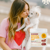 Kaley holding a white dog with a supplement container labeled 'Oh Norman! Minty Fresh AF' in the foreground.